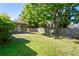 A spacious fenced backyard with a screened-in lanai, mature trees, and green lawn at 16139 Villa Dr, Hudson, FL 34667