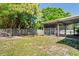 A fenced backyard with grassy lawn, large shade trees, and a screened in porch at 16139 Villa Dr, Hudson, FL 34667