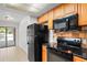 Functional kitchen with black appliances, tile backsplash, and access to a patio at 16139 Villa Dr, Hudson, FL 34667