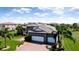 Aerial view of a home featuring a tile roof, brick driveway, three-car garage, and expansive green lawn at 16612 5Th E Ave, Bradenton, FL 34212