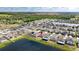 Aerial view of a planned community by a pond, featuring modern homes with well-maintained lawns under a clear, sunny sky at 16633 Sunburst Lake S St, Wimauma, FL 33598