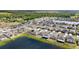 Aerial view of a planned community by a pond, featuring modern homes with well-maintained lawns under a clear, sunny sky at 16633 Sunburst Lake S St, Wimauma, FL 33598