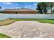 This backyard features a brown house with white fence, green grass, and a brick patio at 1742 Oakwood Estates Dr, Plant City, FL 33563