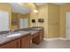 Bathroom with double sinks, granite countertops, wall-mounted TV, and a glass-enclosed shower at 2419 Richmond Greens Ct, Sun City Center, FL 33573