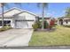 Well-maintained single-story home with an attached two-car garage and lush landscaping on a sunny day at 2419 Richmond Greens Ct, Sun City Center, FL 33573