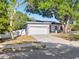 Charming home featuring a two-car garage and a well-maintained front yard with mature trees at 303 National Orange Ave, Oldsmar, FL 34677