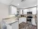 Bright kitchen with white cabinets, granite counters, and stainless steel appliances at 303 National Orange Ave, Oldsmar, FL 34677