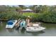 Private dock with three boats and a waterfront home surrounded by lush greenery at 424 Island Cay Way, Apollo Beach, FL 33572