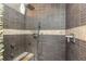Modern shower stall with dark-grey, horizontally-laid tile, a pebble-style accent, and rainfall shower head at 424 Island Cay Way, Apollo Beach, FL 33572