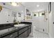 Bright bathroom with black granite counters, tiled shower, modern fixtures, and classic black and white tile flooring at 4701 Rambling River Rd, Brandon, FL 33511