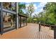 Stunning home exterior featuring a large deck overlooking a lush landscape, mature trees, and blue skies at 4701 Rambling River Rd, Brandon, FL 33511
