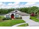 Charming single-story home featuring a manicured lawn, red front door, and attached two-car garage at 5331 Villagebrook Dr, Wesley Chapel, FL 33544
