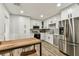 Modern kitchen featuring white cabinetry, stainless steel appliances, and a stylish wooden table with seating at 610 N Woodlynne Ave, Tampa, FL 33609