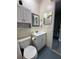 Compact bathroom with a white vanity and toilet, enhanced by storage cabinet and a decorative mirror at 9007 Pebble Creek Dr # 9007, Tampa, FL 33647