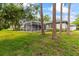The home's exterior is complemented by a lush lawn and a screened-in pool, all enhanced by mature trees at 1003 Berkshire Ln, Tarpon Springs, FL 34688