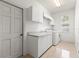 Clean laundry room is equipped with a washer, dryer, sink, and built-in white cabinets at 1003 Berkshire Ln, Tarpon Springs, FL 34688