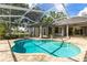 A beautiful backyard pool area featuring stone pavers, screened enclosure, and lush landscaping at 1003 Berkshire Ln, Tarpon Springs, FL 34688