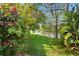 Lush backyard with mature trees, colorful flowers, and a serene view of the lake at 10339 Lightner Bridge Dr, Tampa, FL 33626