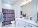 Bright bathroom with a shower with purple curtain, decorative mirror, and marbled countertops at 111 Alafia Estates Ln, Plant City, FL 33567
