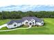 A beautiful white modern farmhouse with dark roof and window frames sits on lush green lawn with mature trees in the background at 111 Alafia Estates Ln, Plant City, FL 33567