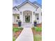 Close up of front entrance of a white brick modern farmhouse with well manicured landscaping and brick walkway at 111 Alafia Estates Ln, Plant City, FL 33567