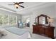 Bright main bedroom with tray ceiling, plantation shutters, and a dresser with large mirror at 14817 Tudor Chase Dr, Tampa, FL 33626
