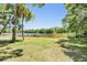 A well-maintained lawn leads to a serene lake framed by mature trees, offering a picturesque backyard setting at 15810 Stanton Ln, Tampa, FL 33647