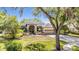 Charming front exterior showcasing lush landscaping, an arched entrance, and a three-car garage at 15810 Stanton Ln, Tampa, FL 33647