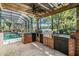 Outdoor kitchen boasts brick construction, built-in grill, sink, and views of the pool and lake at 15810 Stanton Ln, Tampa, FL 33647