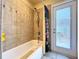 Bathroom features a white bathtub, tiled walls with decorative accents, and access to a deck at 1626 Brooksbend Dr, Wesley Chapel, FL 33543