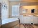 Bright bathroom with double sinks, white cabinets, a garden tub, and a glass block window at 1626 Brooksbend Dr, Wesley Chapel, FL 33543