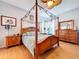 Bright bedroom featuring a four-poster bed, ceiling fan, wood floors, and coordinated furnishings at 1626 Brooksbend Dr, Wesley Chapel, FL 33543