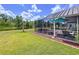A screened in patio with outdoor seating overlooks a green lawn and peaceful water view at 1626 Brooksbend Dr, Wesley Chapel, FL 33543