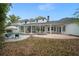 Expansive backyard featuring a pool, brick patio, covered porch, lush lawn, and classic white home exterior at 17062 Comunidad De Avila, Lutz, FL 33548