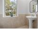 Bright bathroom features neutral tile, pedestal sink, and a window for natural light at 17062 Comunidad De Avila, Lutz, FL 33548
