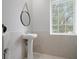 Bathroom with a window view, pedestal sink and a round mirror with rope accent at 17062 Comunidad De Avila, Lutz, FL 33548