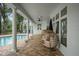 Relaxing covered porch featuring white columns, brick patio, ceiling fans, and a view of the pool and backyard at 17062 Comunidad De Avila, Lutz, FL 33548
