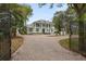 Elegant exterior view of a two-story home with lush landscaping, mature trees, gated entry, and brick circular driveway at 17062 Comunidad De Avila, Lutz, FL 33548