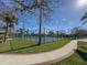Outdoor tennis court surrounded by lush greenery, with ample space for recreation and a sunny sky above at 175 Bath Club N Blvd, North Redington Beach, FL 33708