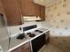 Kitchen with wooden cabinets and white countertops next to white appliances and fruit wallpaper at 1845 S Highland Ave # 6-11, Largo, FL 33756