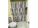 Compact bathroom featuring a toilet and shower with a modern patterned shower curtain at 18607 Bent Pine Dr, Hudson, FL 34667