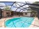 A clear blue swimming pool inside a screen enclosure in a backyard with a covered patio at 1874 Cameo Way, Clearwater, FL 33756