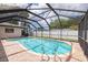 Enclosed screened in pool with clear blue water surrounded by brick pavers in a sunny backyard setting at 1874 Cameo Way, Clearwater, FL 33756