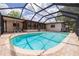 A clear blue swimming pool inside a screen enclosure in a backyard with a covered patio at 1874 Cameo Way, Clearwater, FL 33756