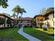 Beautiful condo building with tropical landscaping, sidewalk, and building sign at 2306 Hammock Pine Blvd # 2306, Clearwater, FL 33761