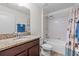Well-lit bathroom with granite countertop, wood vanity, and a shower with decorative seashell-themed curtain at 2404 Dovesong Trace Dr, Ruskin, FL 33570