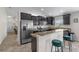 Modern kitchen features stainless steel appliances, dark cabinetry, granite countertops and breakfast bar with stool seating at 2404 Dovesong Trace Dr, Ruskin, FL 33570