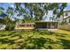 The green backyard of the home shows a covered patio and some trees for shade on a sunny day at 2607 S Bryant Cir, Tampa, FL 33629