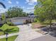 Well-maintained single-story home with a neat front lawn, driveway, and surrounded by mature trees on a sunny day at 2607 S Bryant Cir, Tampa, FL 33629