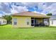 Backyard of home featuring a lawn, screened-in patio with furniture, and yellow siding at 2816 Graphite Ct, Valrico, FL 33594